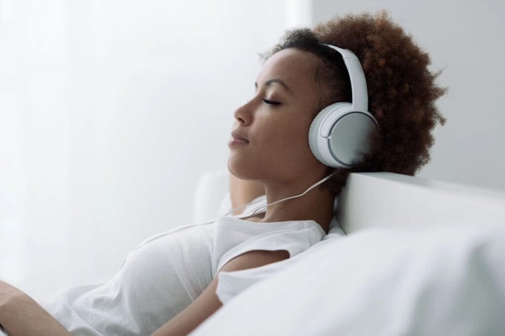 woman closing her eyes while listening to relaxing music on her headphones